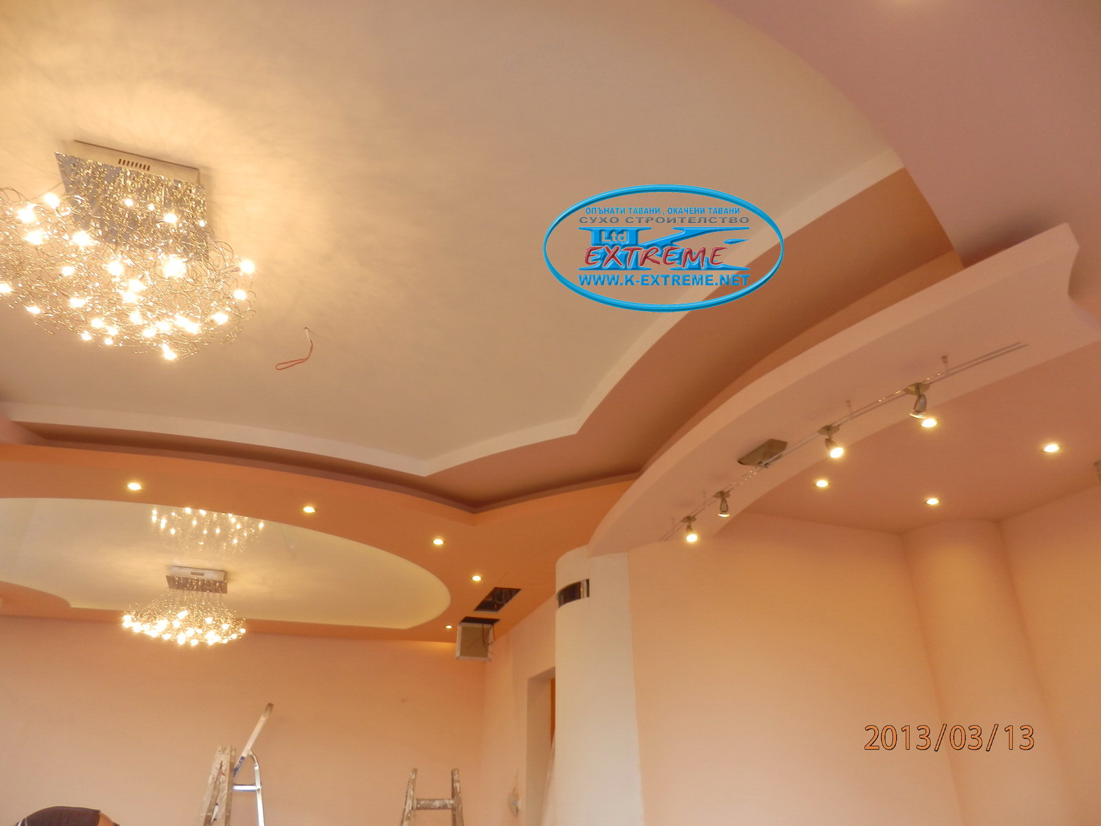 Окачен таван с обли фигури в трапезария и кухня с ниши за скрито осветление, фигура от гипсокартон над барплота, опънат таван в хола - бял гланц.